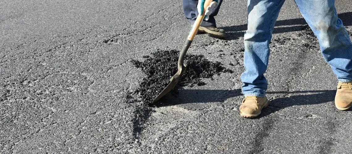 Pothole being repaired with fresh tarmac